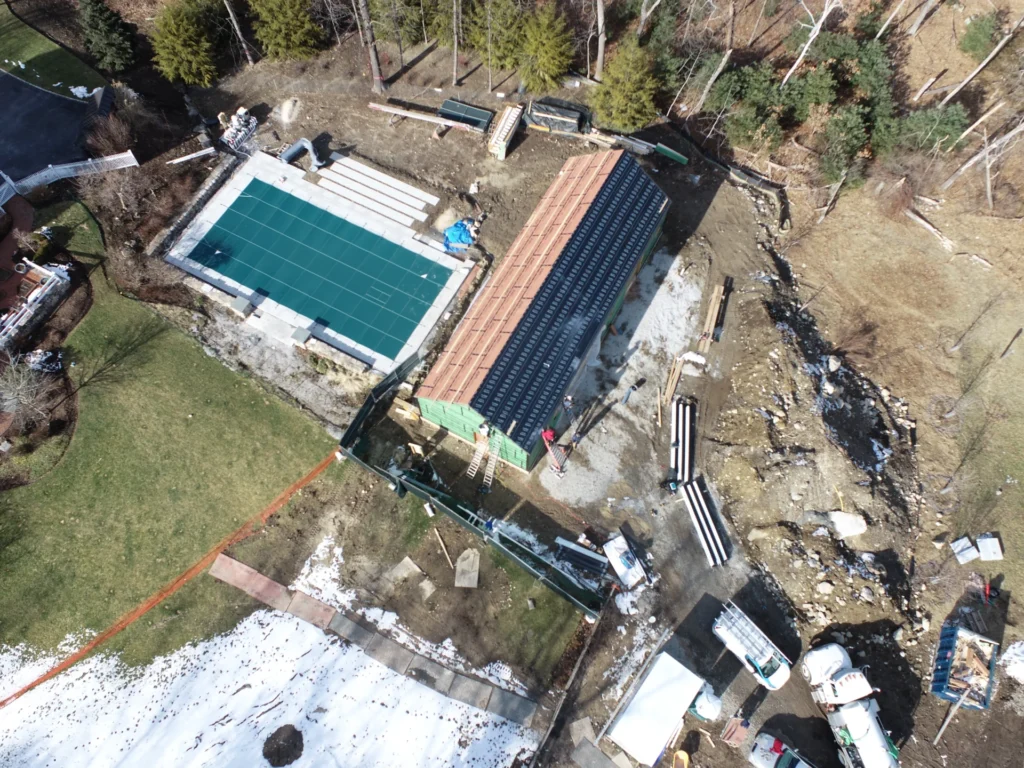 Overhead view of a landscaping construction project, including pools, a building, and a tennis court